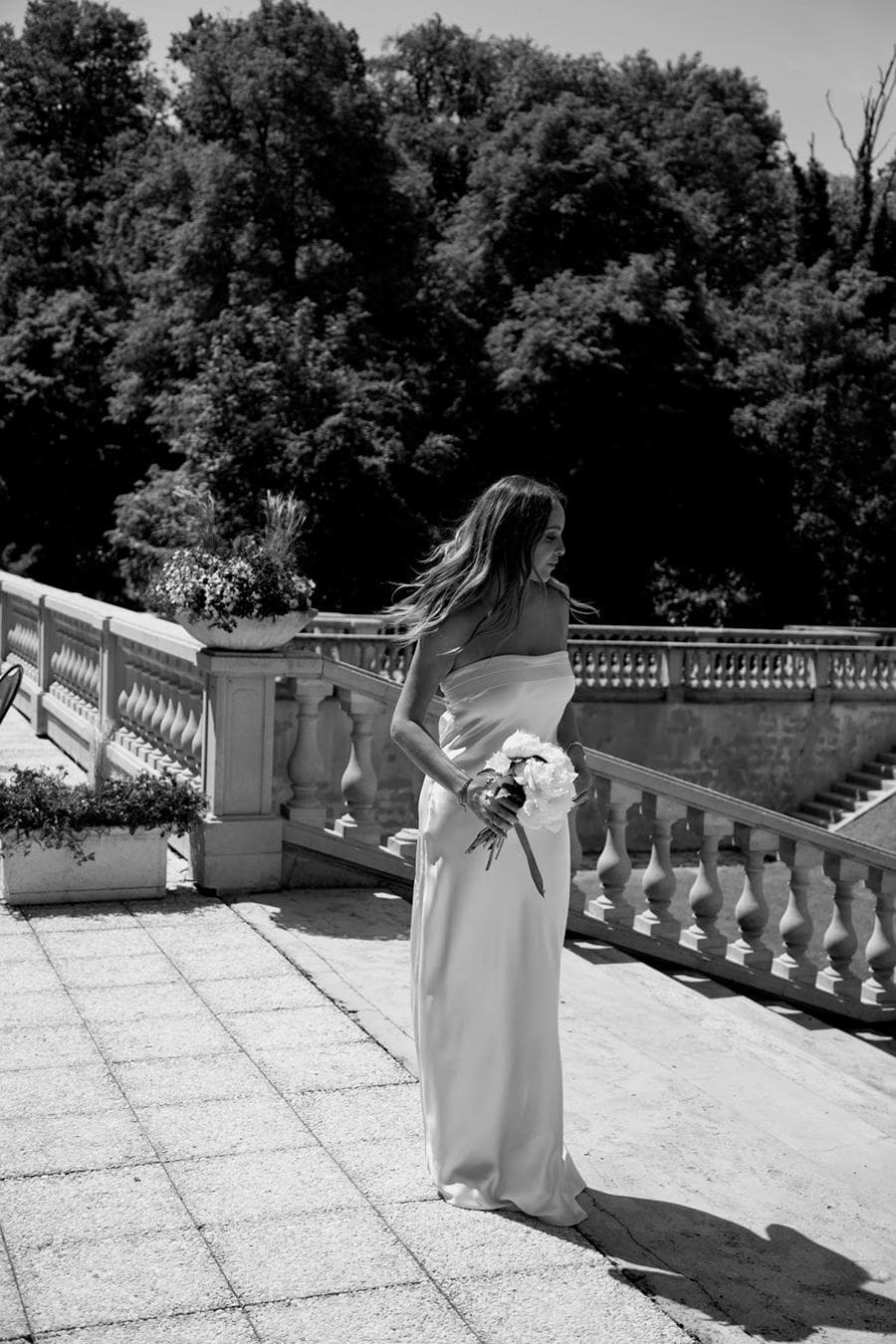 novia mostrando ramo de novia frente a escaleras.